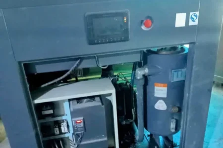 Khoang máy nén khí công nghiệp với bộ điều khiển và thiết bị bên trong khi vỏ máy mở